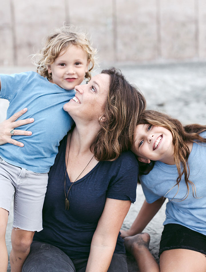 A happy mother holds her two smiling children close.