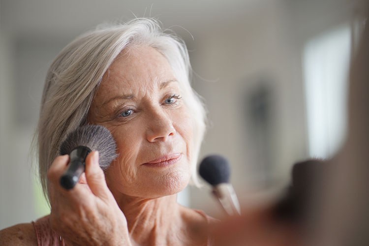 Image of a woman in her fifties applying makeup