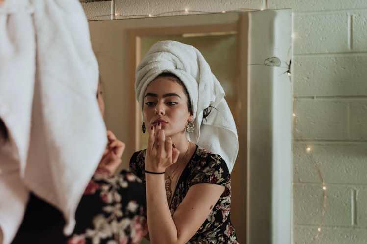 Image of a woman in her twenties applying makeup