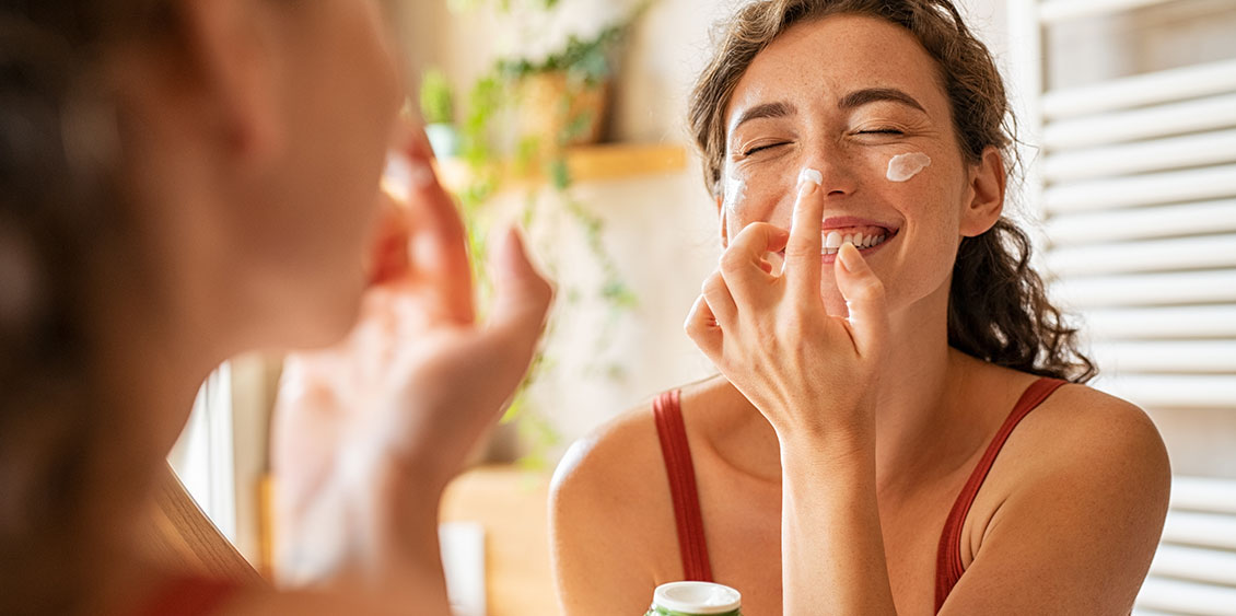 Femme appliquant une crème enrichie en vitamines pour leurs multiples bienfaits pour la peau.