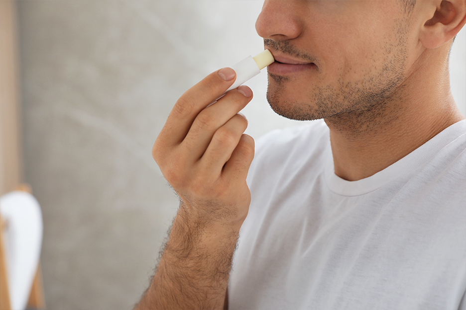 Man applying an effective lip balm to his chapped lips.
