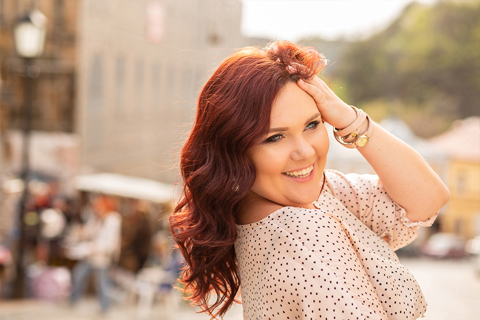 Smiling redhead woman outside in summer with make-up that holds up well even in hot weather.