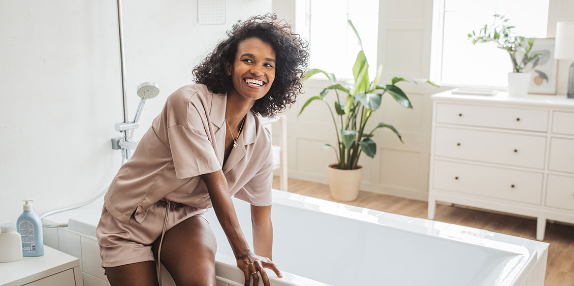 Young woman in bathrobe running a bath in a relaxing setting