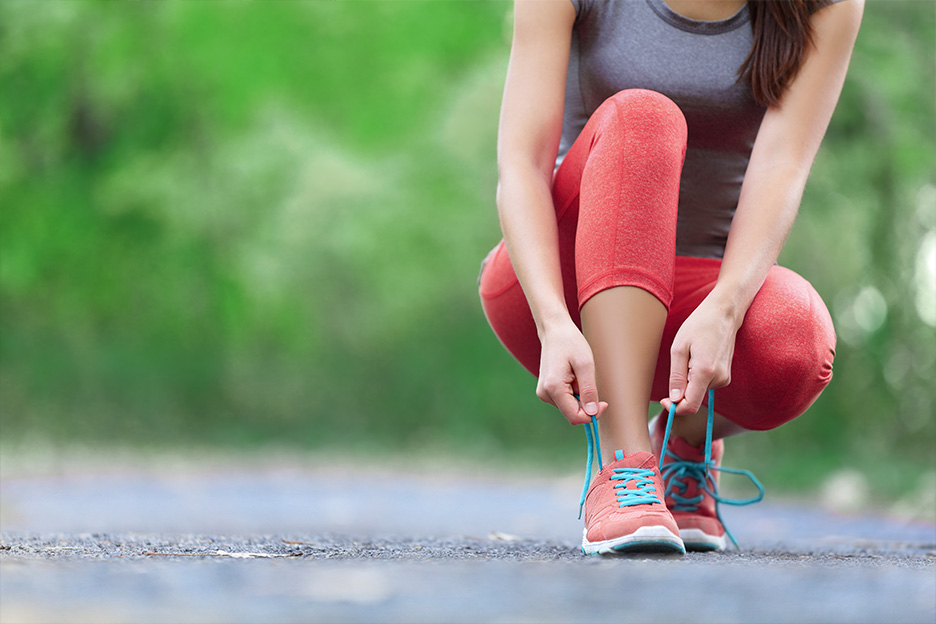 A woman ties her shoelaces while doing outdoor spring activities