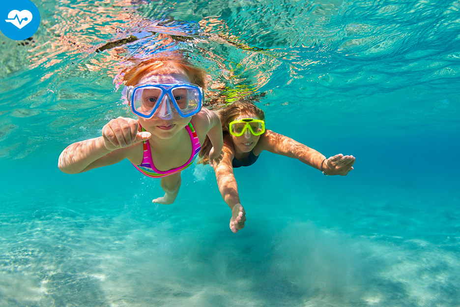 Une petite fille en voyage nage sous l'eau avec sa mère.