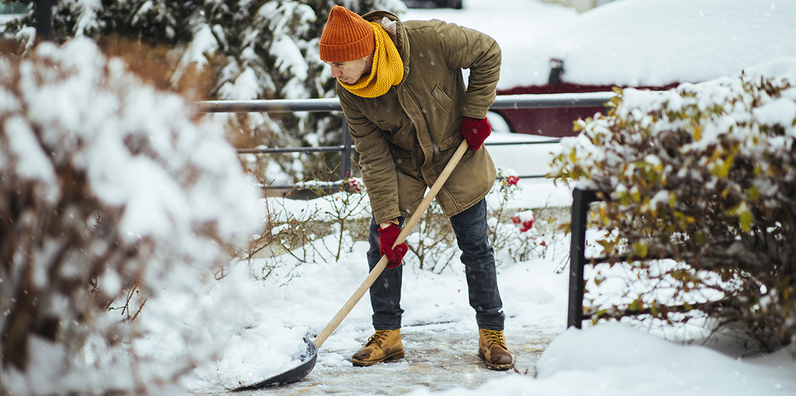 Une personne pellette la neige dans son jardin