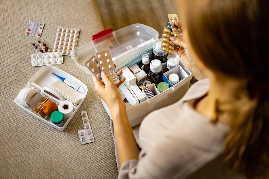 Une femme s'interroge devant le contenu de sa pharmacie.