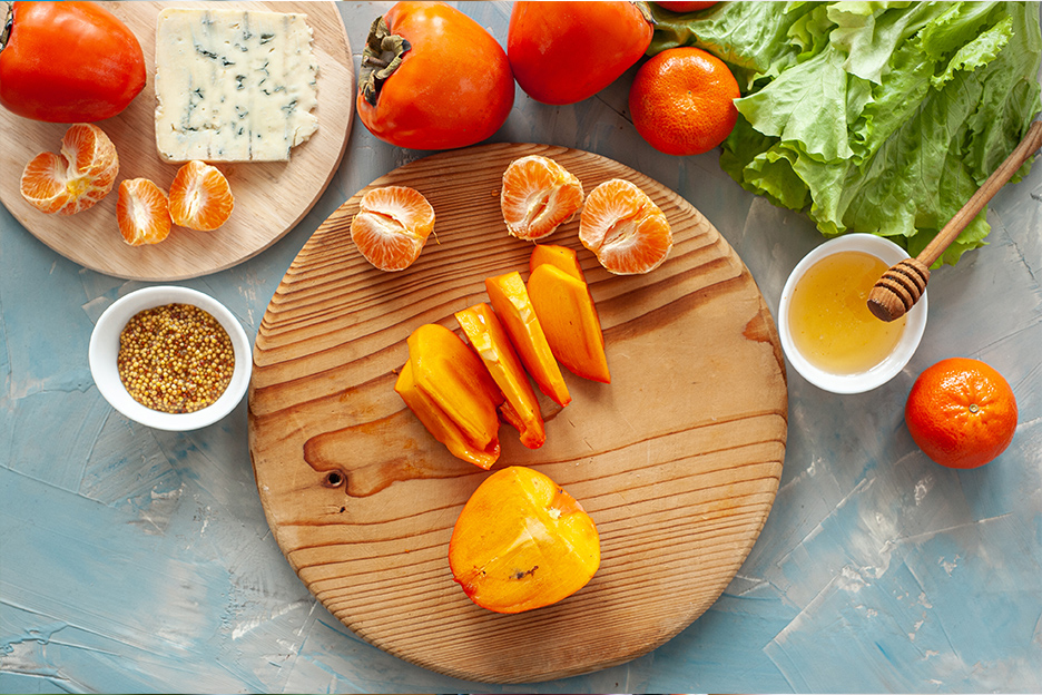 Making a salad with foods rich in vitamin A and beta-carotene: tomatoes, blue cheese, clementines, mandarin oranges, honey, greens, and Dijon mustard.